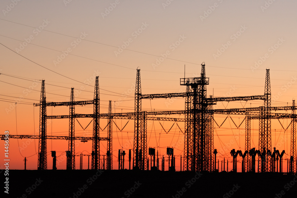 Silhouetted power pylons against a red sky at sunset