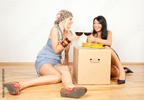 2 frauen mit umzugskiste beim anstossen mit wein photo