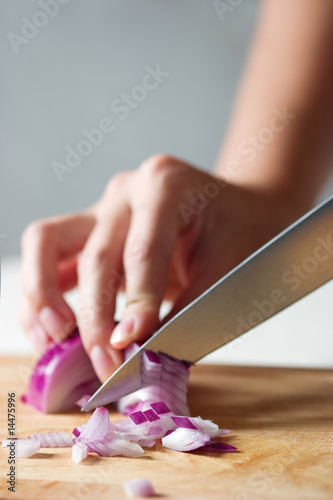 Cutting onion on a wooden cooking table
