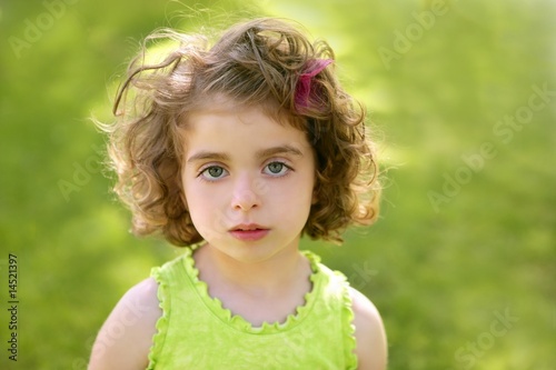 Beautiful brunette blue eyes little girl portrait on grass
