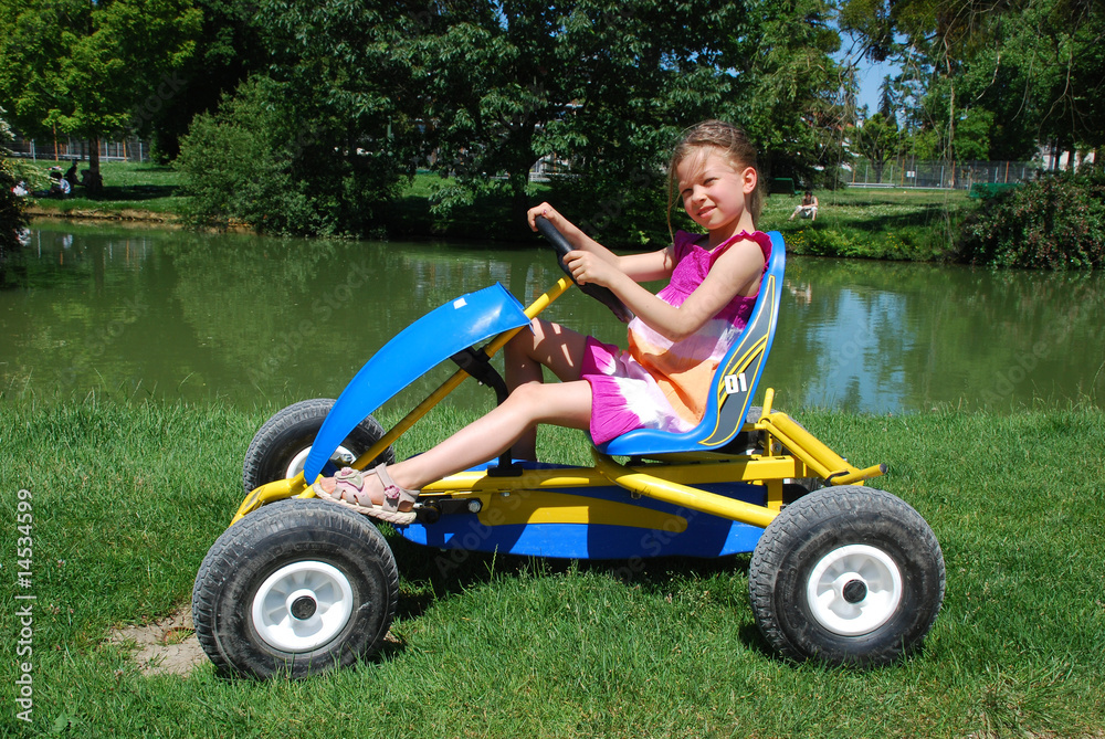 Little girl on the quadrocycle in the border of lake in the park Little girl on the quadrocycle in the border of lake in the park