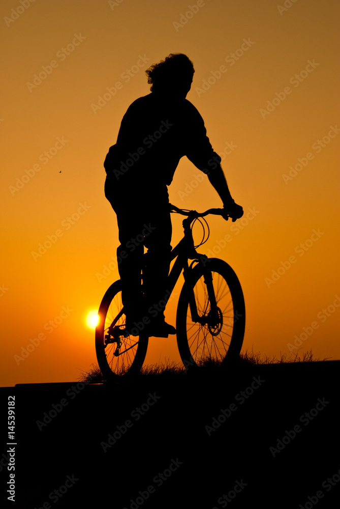 Fototapeta premium silhouet of a young adult riding a bike
