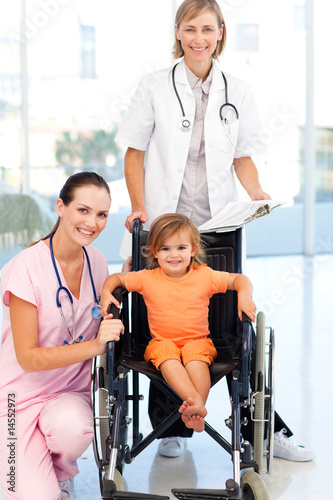 Little girl in a wheelchair doctors looking at the camera