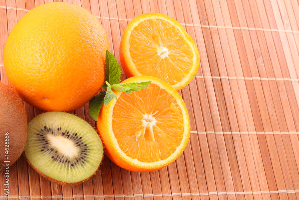 oranges, kiwi and leaves of mint on brown background oranges, kiwi and leaves of mint on brown background