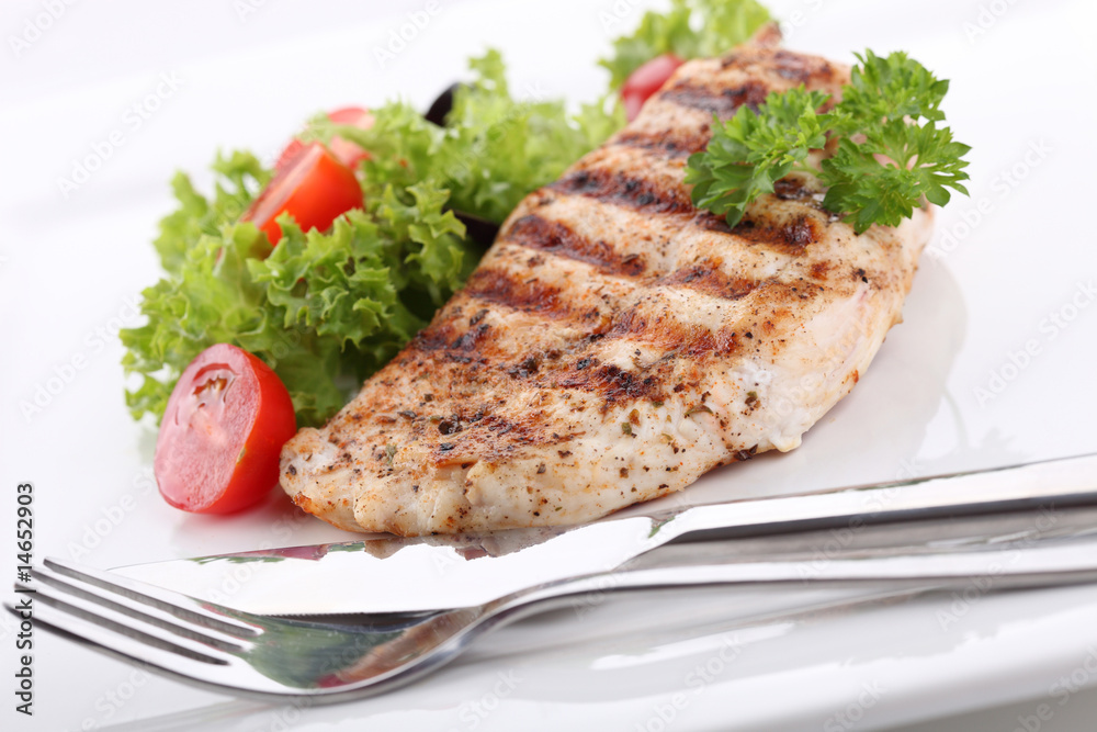 Grilled chicken breasts on a plate with fresh vegetables
