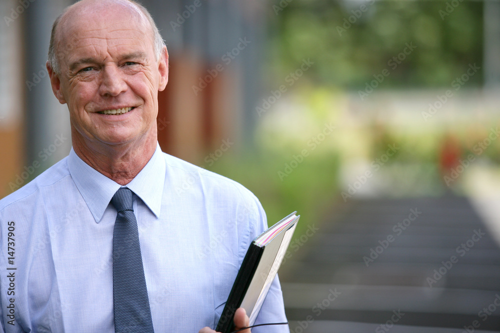Portrait d'un homme senior souriant avec documents à la main Portrait d'un homme senior souriant avec documents à la main