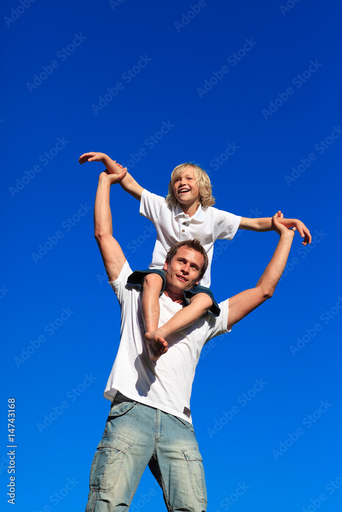 Man giving young boy piggyback ride smiling Man giving young boy piggyback ride smiling