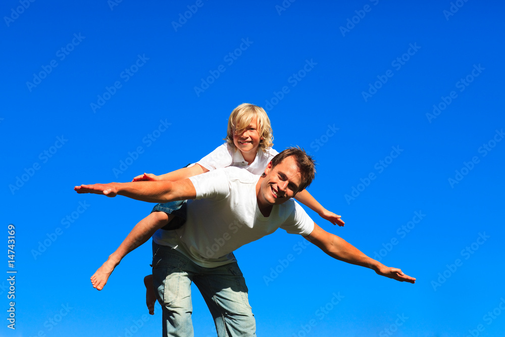 Child on father's back playing airplane Child on father's back playing airplane