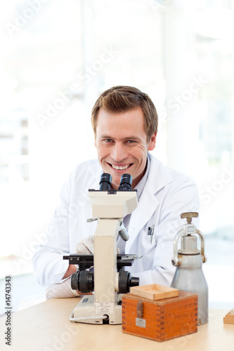 Male scientist looking through a microscope with copy-space