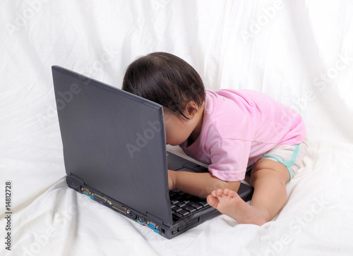 cute baby girl typing on laptop computer photo