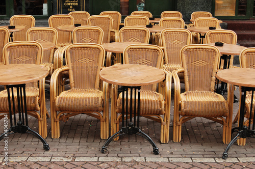 Empty dining tables and rattan wicker chairs in a street cafe