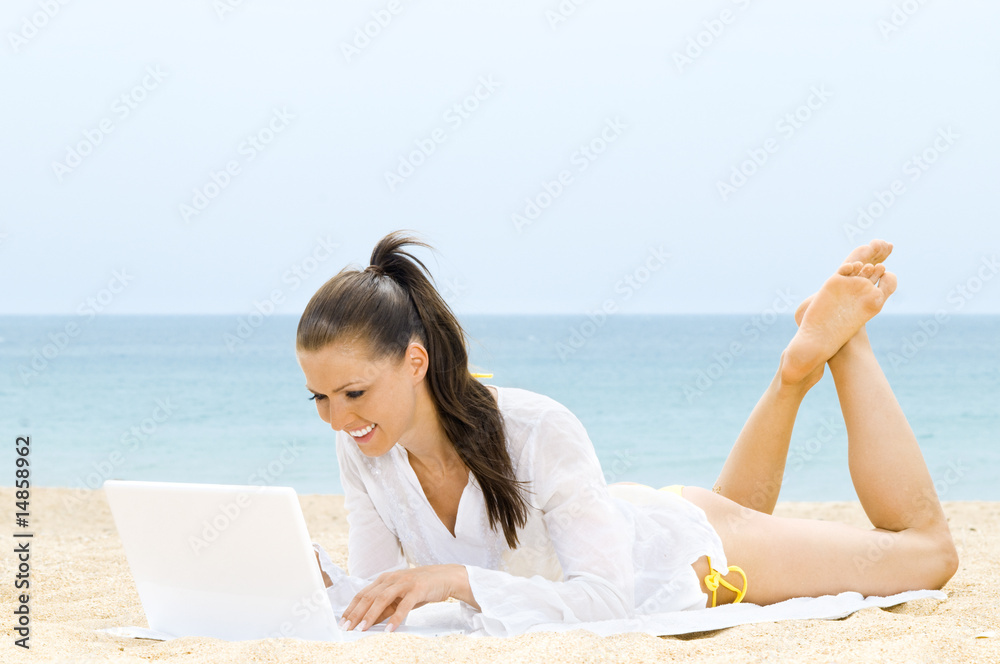Hübsche Frau mit Laptop am Strand