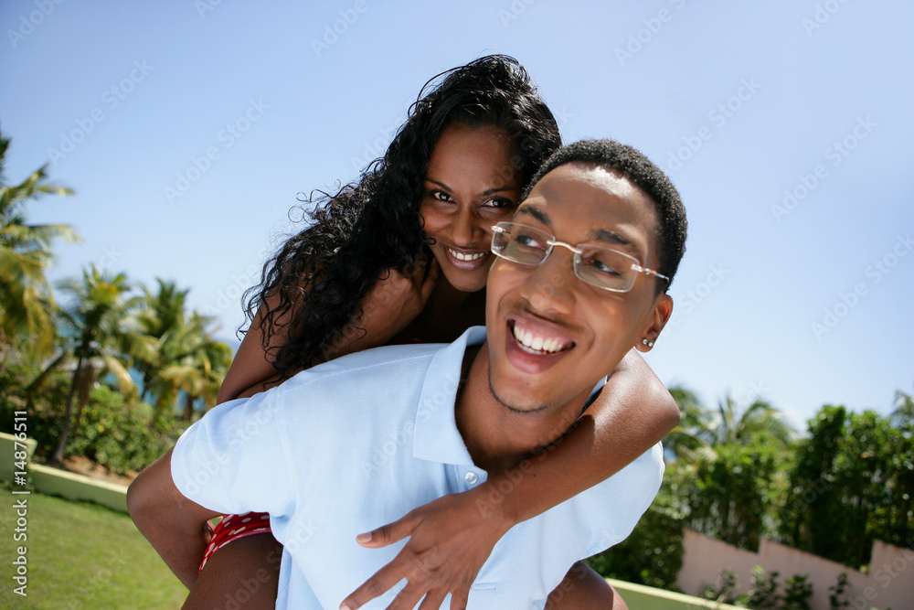 Jeune homme portant une femme souriante sur son dos Jeune homme portant une femme souriante sur son dos