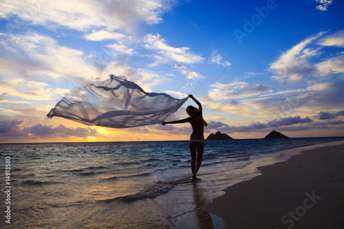 woman in a bikini walking on the beach at sunrise