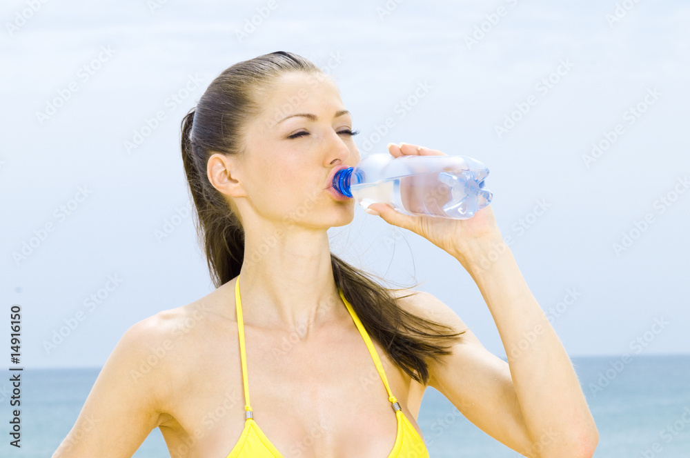 Attraktive Frau trinkt Wasser am Strand Attraktive Frau trinkt Wasser am Strand