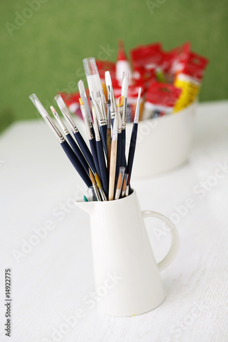 Set of paintbrushes and tubes of paint on a table outdoors.