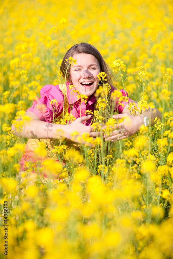 Pretty smiling girl relaxing on green meadow full of yellow flow Pretty smiling girl relaxing on green meadow full of yellow flow