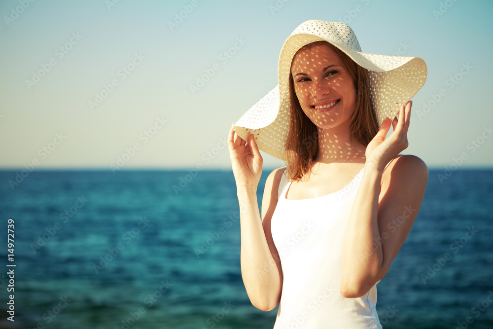 Beautiful girl in a hat on the beach