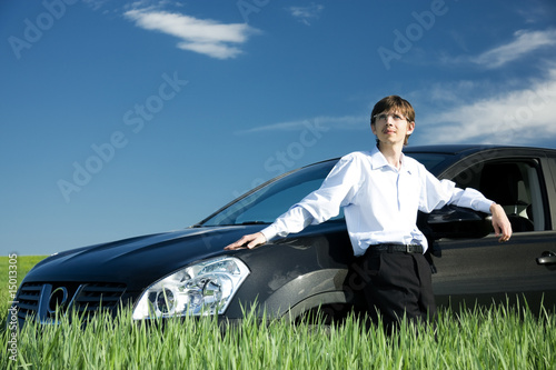 Successful businessman with car on grassland