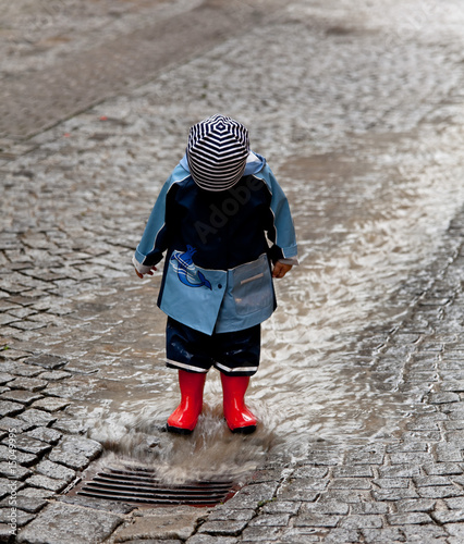 Kind mit Regenkleidung hat Spaß im Regen photo