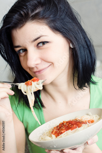 Young woman eating pasta in the kitchen