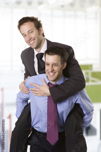 Young smiling businessman piggybacking his colleague
