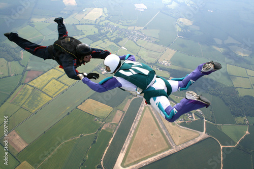 Two skydivers in freefall holding hands