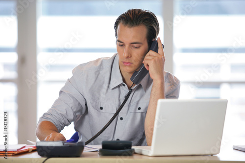 Homme au téléphone devant un ordinateur portable