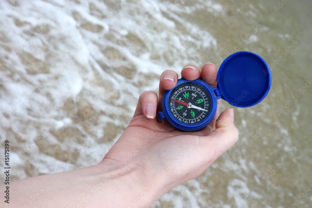Dark blue compass in hands on a background a sea Dark blue compass in hands on a background a sea