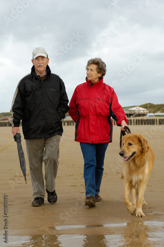 Seniorenpaar mit Hund beim Strandspaziergang photo