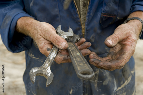 man's greasy hands holding tools