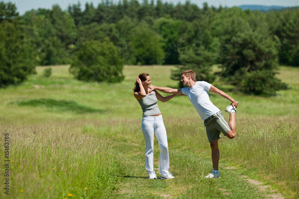 Sportive woman and man stretching outdoors