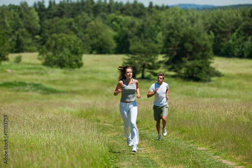 Young woman with headphones jogging in a meadow
