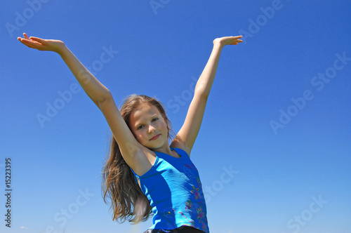 Pretty young girl with arms raised standing on Meadow
