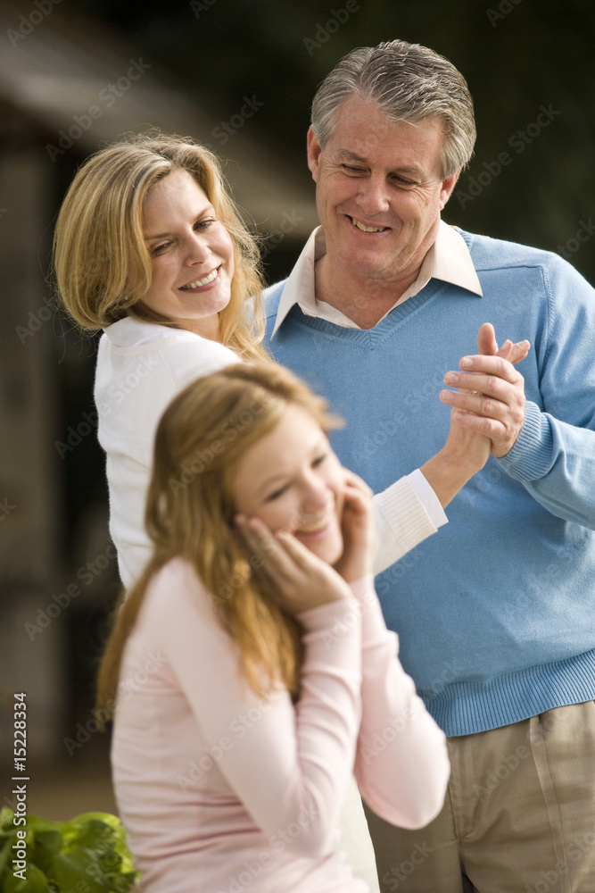 Mature couple dancing outdoors and looking at amused daughter Mature couple dancing outdoors and looking at amused daughter