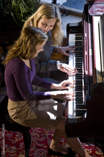 High angle view of mother and daughter playing the piano