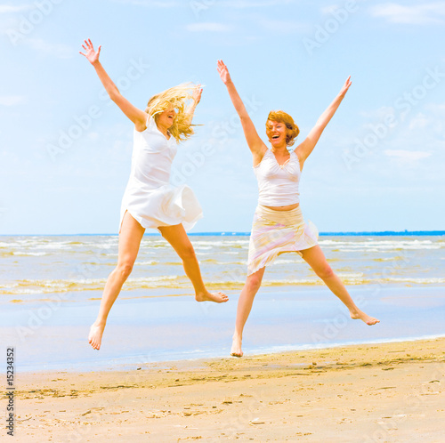 Girls in white jumping happily on a beach