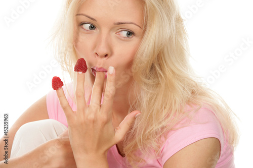 Portrait of young woman eating raspberries off fingers