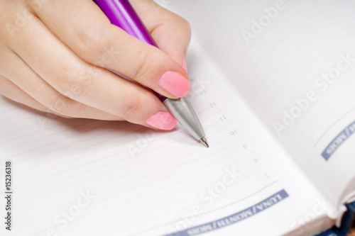 Hand writing in a notebook with pen