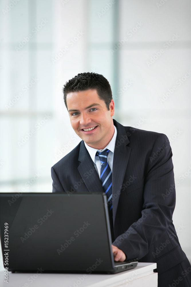 Homme d'affaires souriant en costume avec un ordinateur portable Homme d'affaires souriant en costume avec un ordinateur portable