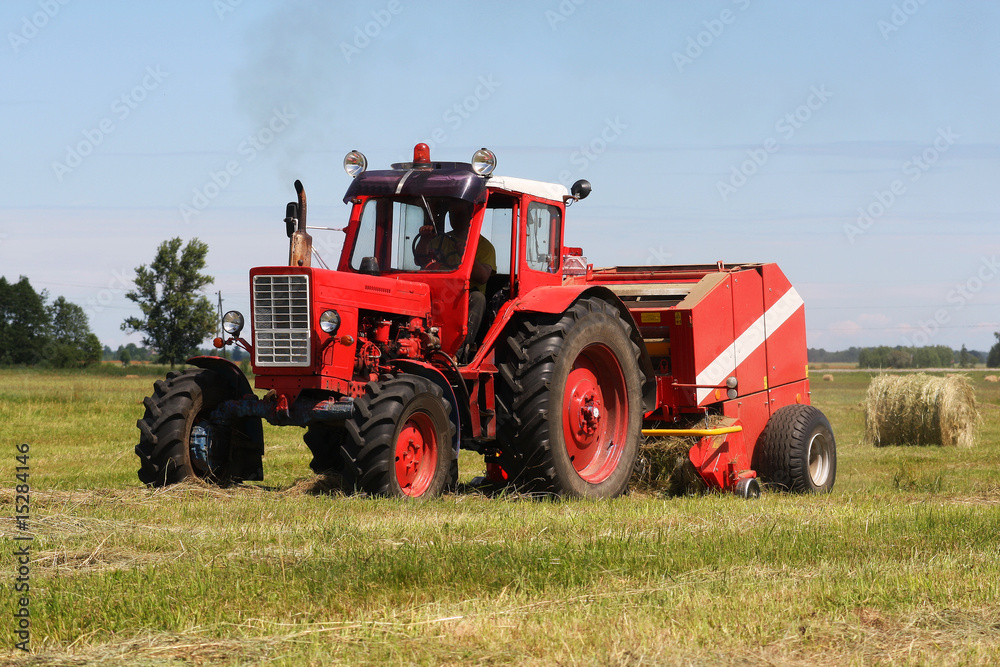 Red tractor working in the field (focus on a tractor) Red tractor working in the field (focus on a tractor)