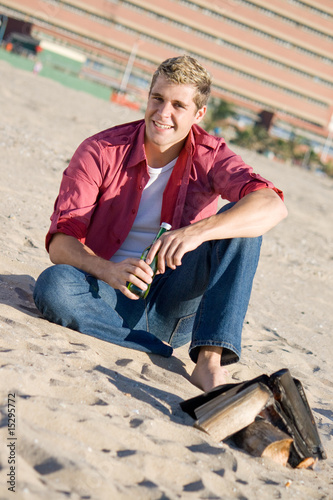 young man on beach drinking a beer