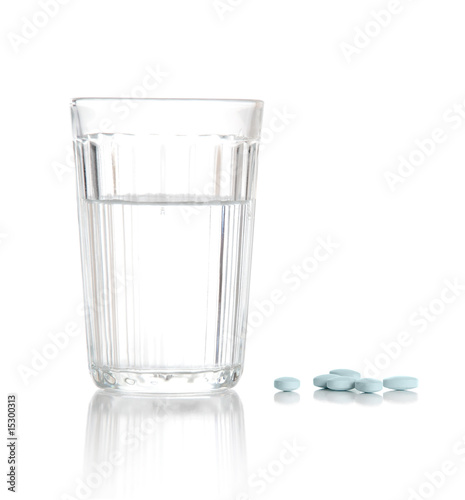 Glass with water and a heap of tablets, pills