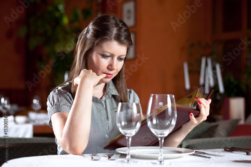 girl chooses meal under the menu at restaurant