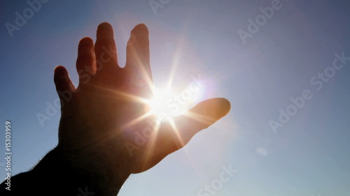 Hand in silhouette raised up to the sun
