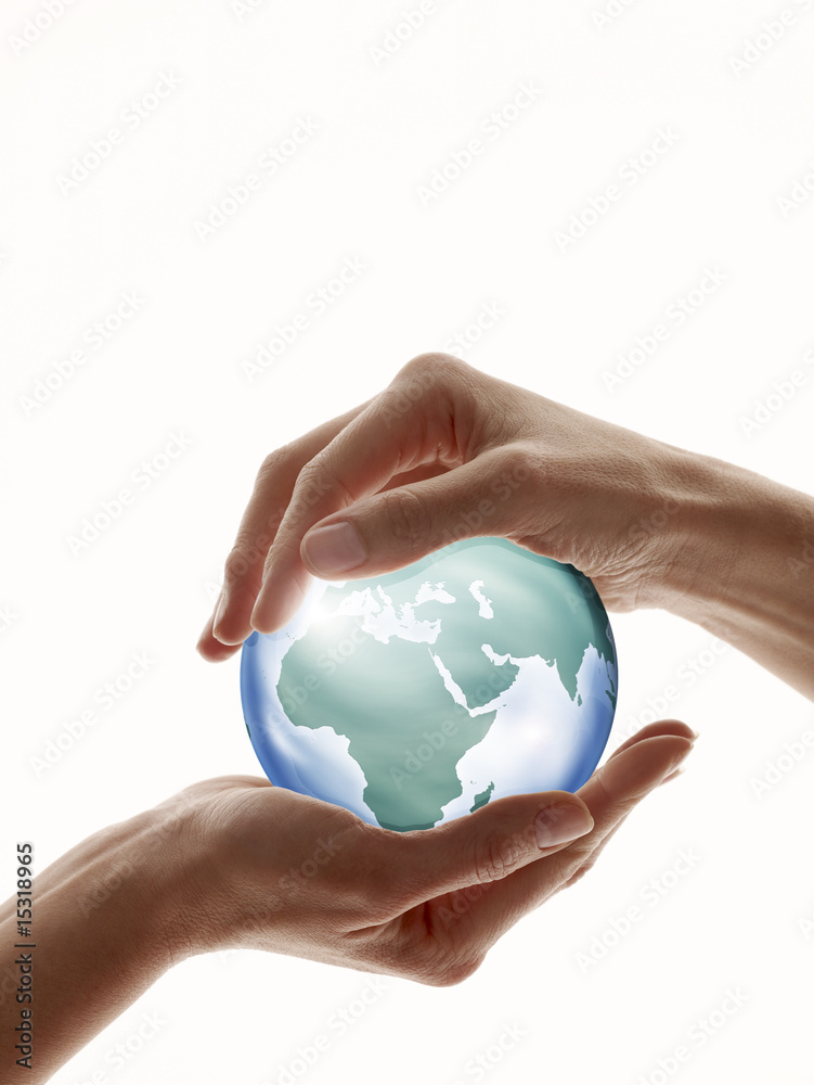 Two hands encircling a digitally created glass globe Two hands encircling a digitally created glass globe