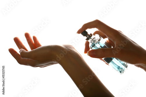 woman applying perfume on her wrist, bright red perfume bottle