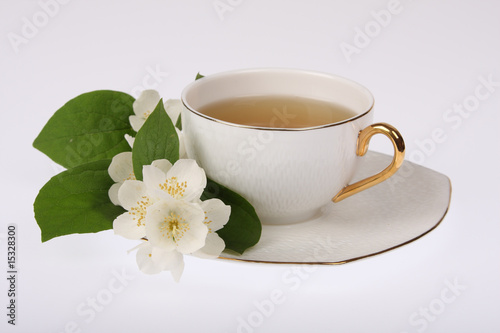 White cup of tea with jasmine flowers isolated on white