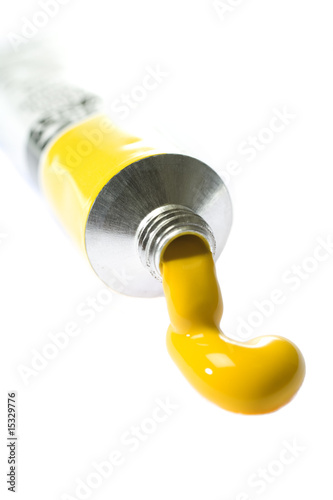 Yellow paint coming from tube on white background