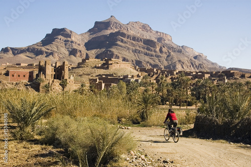 Girl cycling in the desertic Draa Valley, Morocco